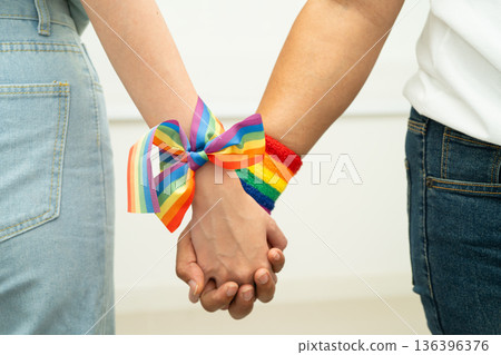 Asian LGBT couple woman holding hand wearing rainbow wristband. Asian LGBT couple woman holding hand wearing rainbow wristband. 136396376