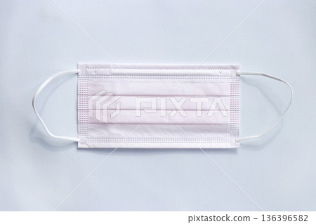 A four-layer pleated nonwoven mask laid flat on a white background. A daily hygiene product. A four-layer pleated nonwoven mask laid flat on a white background. A daily hygiene product. 136396582