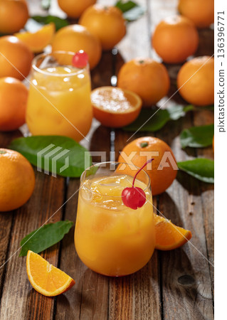 Orange juice garnished with red cherry. 136396771