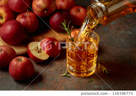 Apple kombucha is poured from a bottle into a glass. 136396773