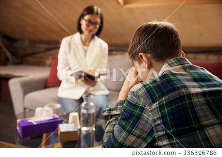 Teenage boy in psychotherapy session with professional psychologist. Teenage boy in psychotherapy session with professional psychologist. 136396786