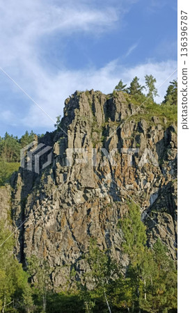 A stunning view of a rugged cliff face adorned with trees, offering a captivating scene for travel, tourism, or environmental projects. It provides an excellent backdrop for adventure-themed content. A stunning view of a rugged cliff face adorned with trees, offering a captivating scene for travel, tourism, or environmental projects. It provides an excellent backdrop for adventure-themed content. 136396787