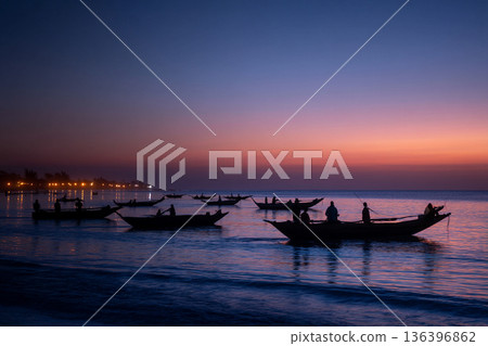 The serene scene of Comorian artisanal fishing boats returning to shore at dusk, their lights twinkling on the horizon. The serene scene of Comorian artisanal fishing boats returning to shore at dusk, their lights twinkling on the horizon. 136396862