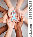 A diverse group of hands holds a diabetes awareness ribbon, symbolizing unity and collective support. 136397088