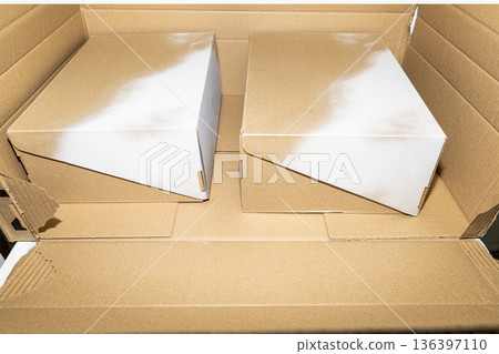 Open cardboard box containing two shoe boxes. 136397110