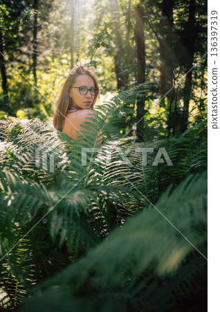 Woman in Sunlit Forest Surrounded by Ferns Woman in Sunlit Forest Surrounded by Ferns 136397319