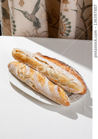 Freshly baked assorted baguettes on white plate Freshly baked assorted baguettes on white plate 136397807