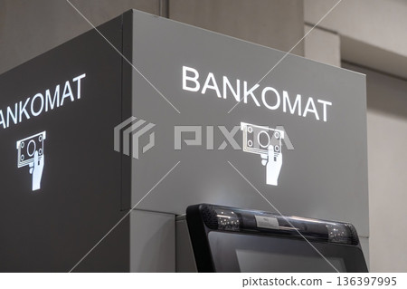 Illuminated BANKOMAT sign displays clear graphic of hand with money, representing swift, easy automated teller machine services for quick financial transactions 136397995
