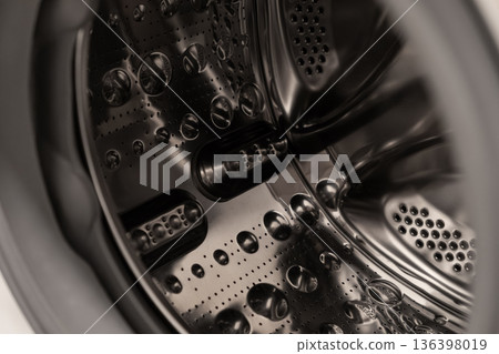Clean empty modern washing machine drum interior, showcasing perforated stainless steel surface and textured paddles for efficient household laundry 136398019