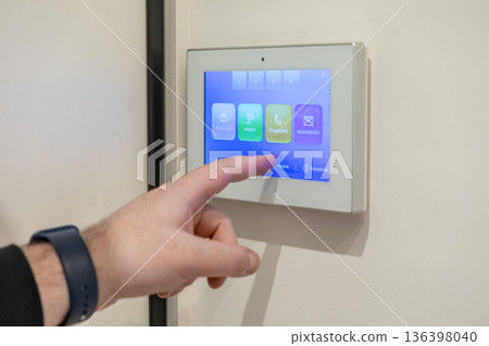 Person interacts with a modern smart home intercom system, touching its vibrant touchscreen display for security and convenient building access management Person interacts with a modern smart home intercom system, touching its vibrant touchscreen display for security and convenient building access management 136398040