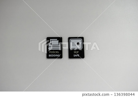 Two black hotel amenity signs, with white icons and text, highlighting available bedding and safe services for guests, emphasizing comfort and security 136398044