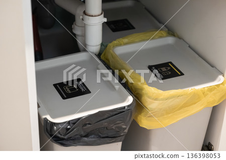 Organized under-sink waste segregation bins display clear labels for mixed waste and plastic metal, promoting efficient household recycling 136398053