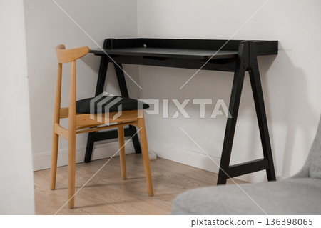 A sleek black minimalist desk and natural wood chair form a functional home office corner, embodying modern interior design and productivity A sleek black minimalist desk and natural wood chair form a functional home office corner, embodying modern interior design and productivity 136398065