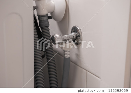 Modern chrome water tap valve securely connecting a grey hose for washing machine, ensuring efficient home plumbing and reliable utility Modern chrome water tap valve securely connecting a grey hose for washing machine, ensuring efficient home plumbing and reliable utility 136398069