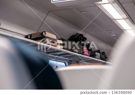 Various pieces of travel luggage are stored securely on the overhead rack inside a modern train cabin, symbolizing efficient public transport and passenger storage solutions Various pieces of travel luggage are stored securely on the overhead rack inside a modern train cabin, symbolizing efficient public transport and passenger storage solutions 136398090