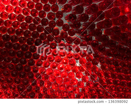 Vibrant red glass bottles artfully arranged and illuminated from behind, forming a captivating abstract pattern and modern design installation, evoking luxury and celebration 136398092