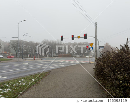 City street intersection with multiple red traffic lights on a foggy day, emphasizing urban travel conditions and safety for drivers and pedestrians 136398119