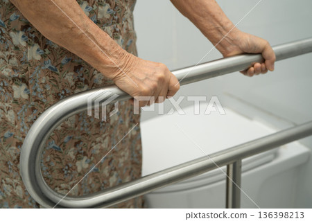 Asian elderly woman patient use handrail safety in toilet support rail in bathroom. Asian elderly woman patient use handrail safety in toilet support rail in bathroom. 136398213