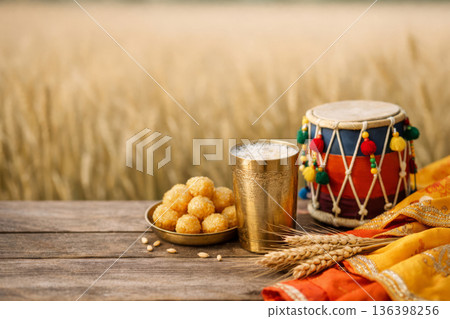 Vaisakhi harvest festival concept featuring Punjabi culture symbols, delicious food and festive dhol on blurred wheat farm. 136398256