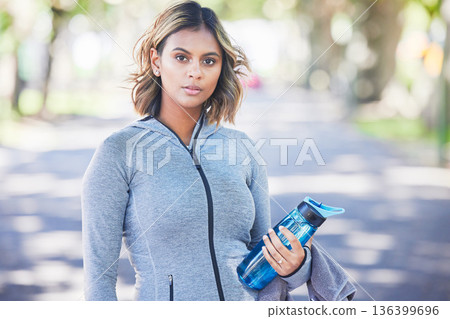 Runner woman, bottle and portrait in park, ready and exercise with fitness training in nature. Indian girl, commitment and pride for wellness, health or outdoor workout for body, self care or goals 136399696