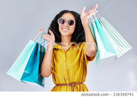 Sunglasses, portrait and woman with shopping bag for fashion in studio isolated on a white background. Face smile, sales and African customer with gift, discount deal and clothes from retail store Sunglasses, portrait and woman with shopping bag for fashion in studio isolated on a white background. Face smile, sales and African customer with gift, discount deal and clothes from retail store 136399741
