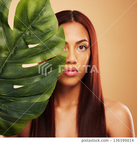 Beauty, leaf and portrait of woman in studio for natural dermatology, cosmetics or wellness results. Skin care, nature and monstera plant for eco friendly facial of model person on brown background Beauty, leaf and portrait of woman in studio for natural dermatology, cosmetics or wellness results. Skin care, nature and monstera plant for eco friendly facial of model person on brown background 136399814