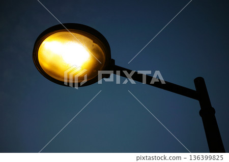 Glowing street lamp against dark blue night sky Glowing street lamp against dark blue night sky 136399825