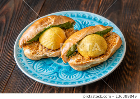 Authentic Vada Pav Indian street food with spicy chutney on rustic wooden background Authentic Vada Pav Indian street food with spicy chutney on rustic wooden background 136399849