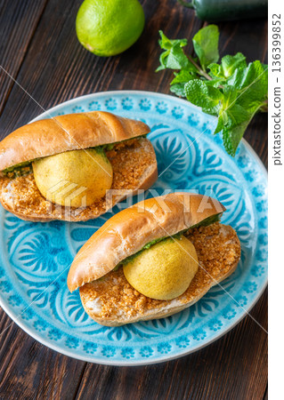 Authentic Vada Pav Indian street food with spicy chutney on rustic wooden background 136399852