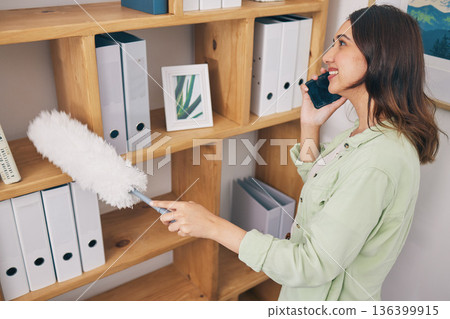 Cleaning, phone call and dust with woman in office for housekeeping service, communication and sanitary. Contact, networking and conversation with female cleaner and bookshelf for chat and hygiene 136399915