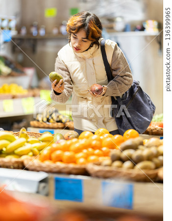 Young woman chooses mango in store 136399965