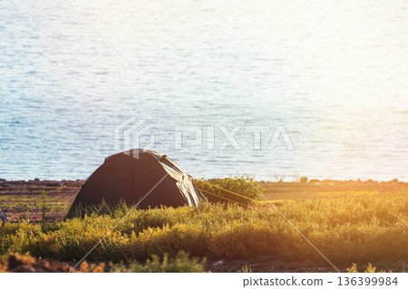 Serene camping scene with a green tent by a blue lake Bartogai, surrounded by lush steppe greenery in Kazakhstan. Serene camping scene with a green tent by a blue lake Bartogai, surrounded by lush steppe greenery in Kazakhstan. 136399984
