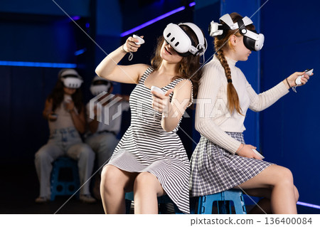 Girl in headset playing VR games against each other in room 136400084