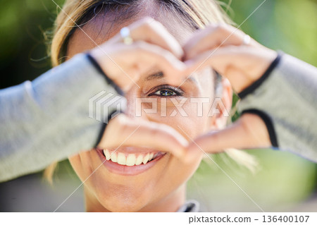 Nature, portrait and heart hands of a woman for exercise, training and an outdoor workout. Smile, closeup and face of a young athlete or runner with a gesture for love of fitness or running in a park 136400107