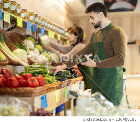 Man seller in grocery vegetable shop arrange cucumber case 136400195