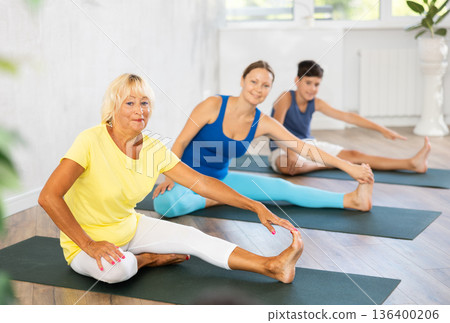 Son, mother and grandmother do yoga doing Janu Sirsasana exercise 136400206