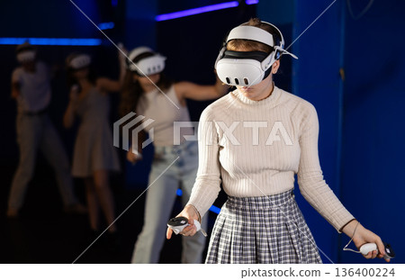 Young female in VR goggles playing virtual reality game Young female in VR goggles playing virtual reality game 136400224