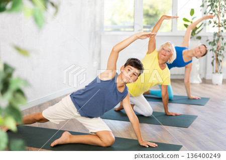 Preteen boy practicing half side plank pose of yoga in light fitness room Preteen boy practicing half side plank pose of yoga in light fitness room 136400249