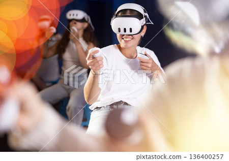 Young woman immersed in virtual reality game in gaming center Young woman immersed in virtual reality game in gaming center 136400257