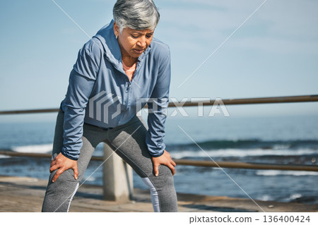 Senior, exercise and tired woman at the beach on break from training, workout or morning cardio run in nature. Sports, fatigue and elderly female runner stop to breathe on ocean workout or fitness Senior, exercise and tired woman at the beach on break from training, workout or morning cardio run in nature. Sports, fatigue and elderly female runner stop to breathe on ocean workout or fitness 136400424