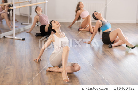 Young woman practicing vogue dance moves on floor at group class Young woman practicing vogue dance moves on floor at group class 136400452
