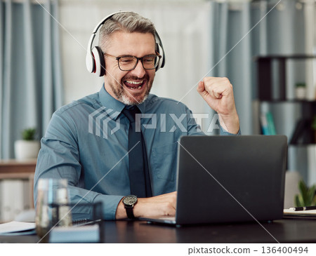 Celebrate, headphones and businessman working on a laptop with good news or achievement. Happy, excited and mature professional male designer in celebration for job promotion or success in workplace. 136400494