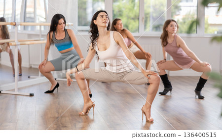 Girls in heels learn to move to beat of music and combine rhythm and smooth movements 136400515