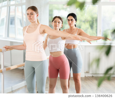 Young girl maintaining second position at ballet barre during group rehearsal Young girl maintaining second position at ballet barre during group rehearsal 136400626