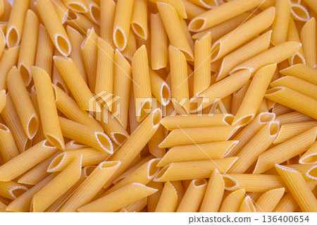 Closeup of penne pasta textures, Macro image highlighting golden segmented pasta, Highresolution photograph emphasizing detailed semolina surfaces and golden ridges of pasta Closeup of penne pasta textures, Macro image highlighting golden segmented pasta, Highresolution photograph emphasizing detailed semolina surfaces and golden ridges of pasta 136400654