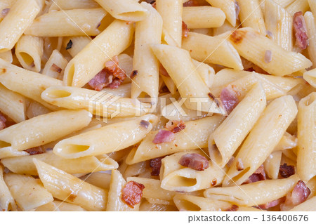 Creamy penne tossed with fried bacon bistro chef plating inspiration, closeup texture of al dente tubes, golden cheese melt, herb oil sheen, menu photographyready composition 136400676