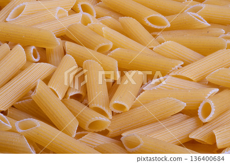 Focused shot of pasta variety, Closeup of yellow pasta showing porous and abundant quality, Upclose view emphasizing detailed porous texture and plentiful pasta arrangement 136400684