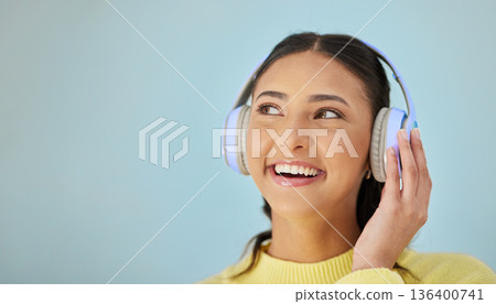 Woman with smile, headphones and mockup in studio thinking with technology on mobile app and streaming radio site. Podcast, music media subscription and happy girl with sound on blue background space 136400741