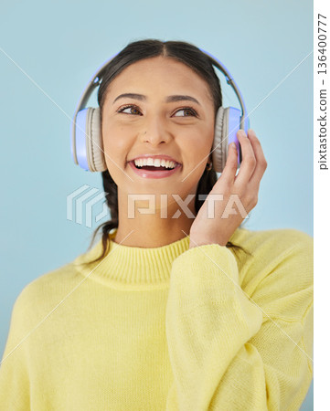 Woman with smile, headphones and mockup in studio for podcast, mobile app and streaming radio site. Sound, music subscription and happy girl listening to audio on earphones on blue background space. 136400777