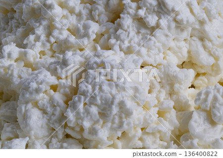 Granular cottage cheese with subtle yellow whey under natural light, Detailed closeup of fresh cottage cheese granules with warm farmstyle ambiance and subtle yellow whey Granular cottage cheese with subtle yellow whey under natural light, Detailed closeup of fresh cottage cheese granules with warm farmstyle ambiance and subtle yellow whey 136400822